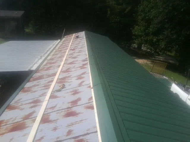 Old rusted panels beside newly installed green metal roofing — Wind Damage Roof Repair by Roofing Brothers in Camden